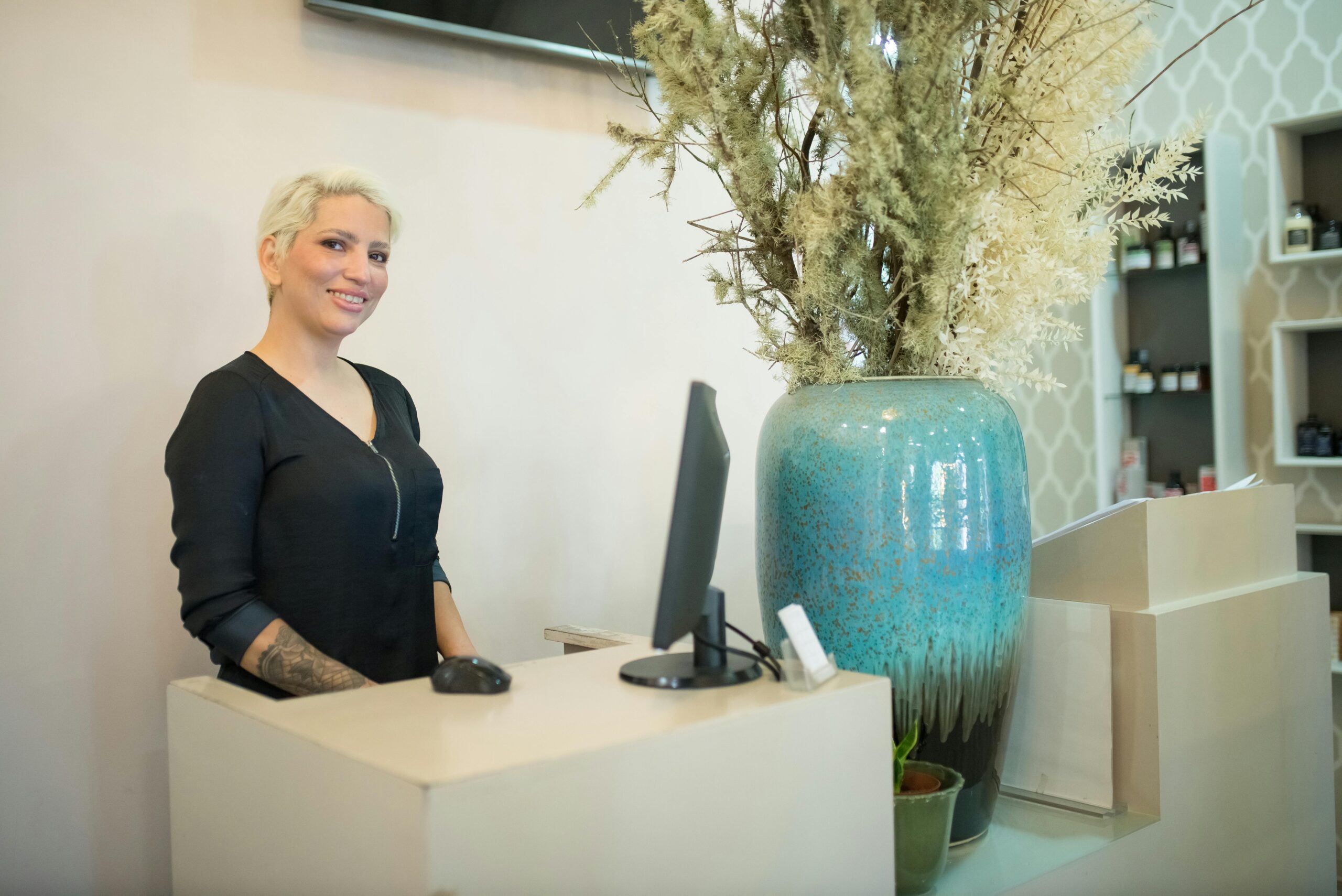 A stock image of a woman standing behind a counter to illustrate the blog post How to Handle Clients Who Question Your Pricing and Protect Your Wellness Business Model